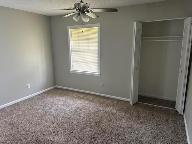 unfurnished bedroom with carpet flooring, a textured ceiling, a ceiling fan, baseboards, and a closet
