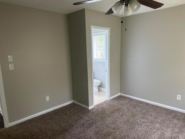 unfurnished bedroom featuring carpet floors, a ceiling fan, baseboards, and ensuite bathroom