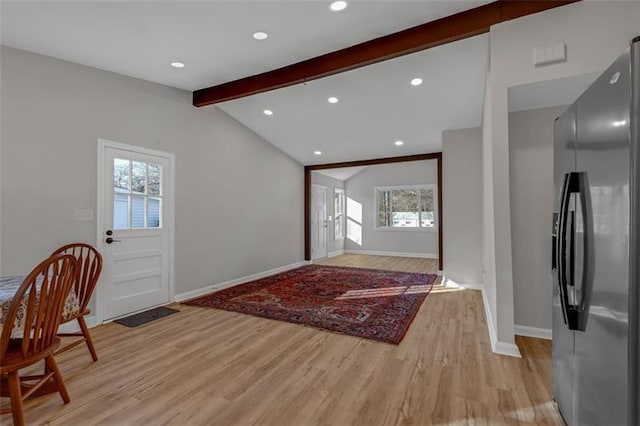 foyer featuring a wealth of natural light, lofted ceiling with beams, and light hardwood / wood-style flooring