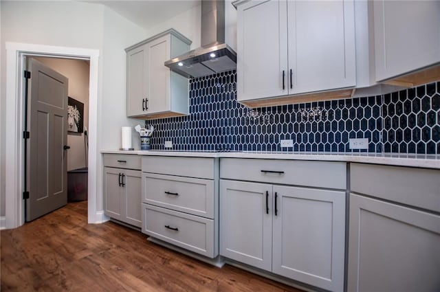 kitchen with backsplash, dark hardwood / wood-style flooring, and wall chimney range hood