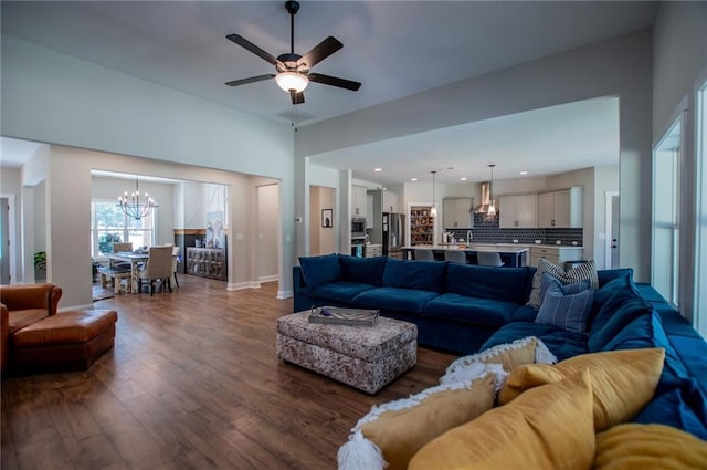 living room featuring ceiling fan with notable chandelier and dark wood-type flooring