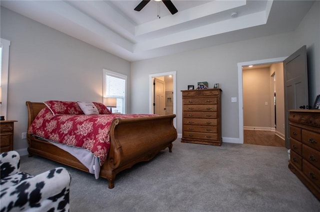 bedroom featuring ceiling fan, ensuite bathroom, a raised ceiling, and carpet floors