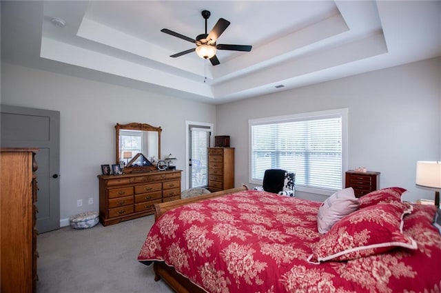 carpeted bedroom with a raised ceiling and ceiling fan