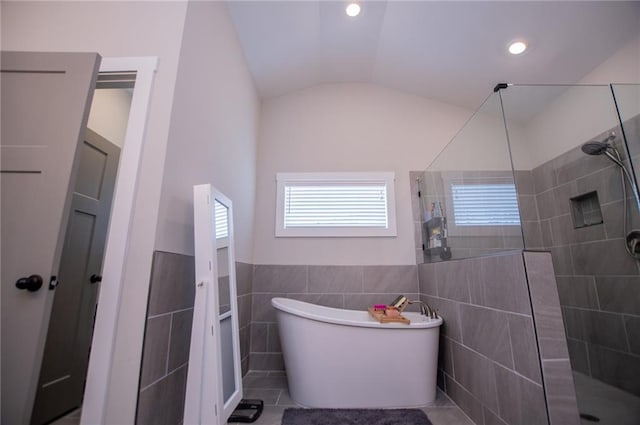 bathroom with separate shower and tub, vaulted ceiling, and tile walls