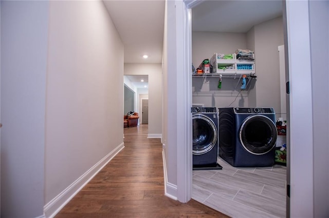 clothes washing area with washing machine and clothes dryer and light hardwood / wood-style floors