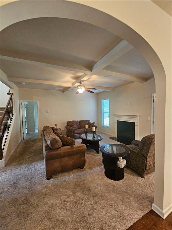living area with baseboards, stairs, a fireplace, beamed ceiling, and a ceiling fan