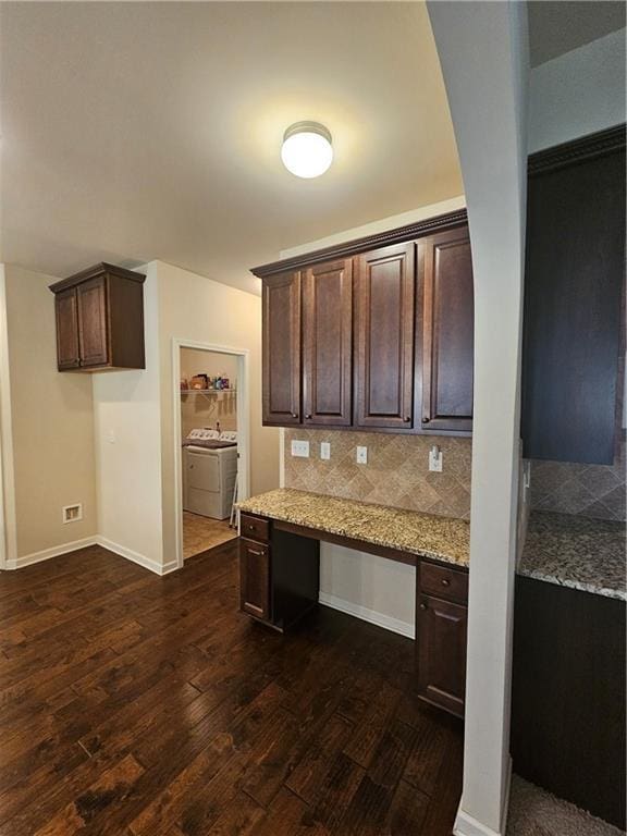 kitchen featuring dark wood-type flooring, dark brown cabinets, light stone countertops, and baseboards
