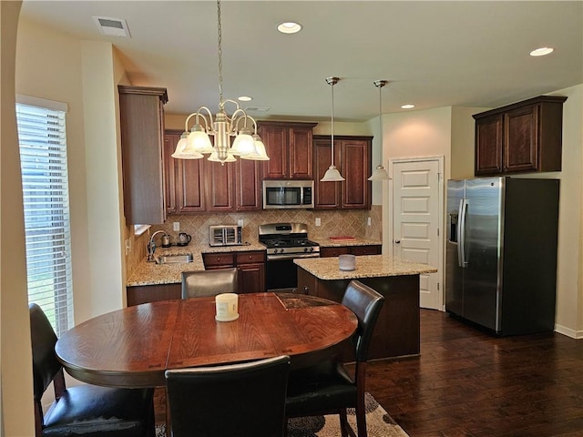 1750 Stone Meadow Rd, Lithonia, GA 30058 - kitchen with appliances with stainless steel finishes, dark wood-style flooring, a chandelier, a center island, and decorative backsplash