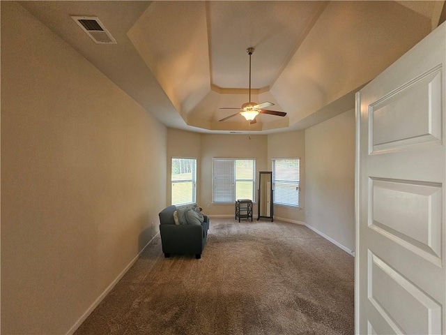 unfurnished room with a raised ceiling, ceiling fan, carpet flooring, and baseboards