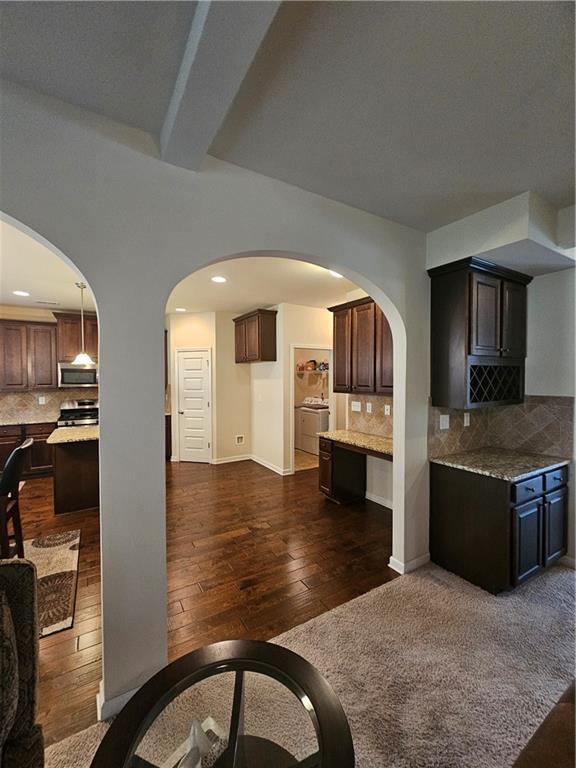 1750 Stone Meadow Rd, Lithonia, GA 30058 - kitchen with stainless steel microwave, dark wood finished floors, backsplash, arched walkways, and recessed lighting