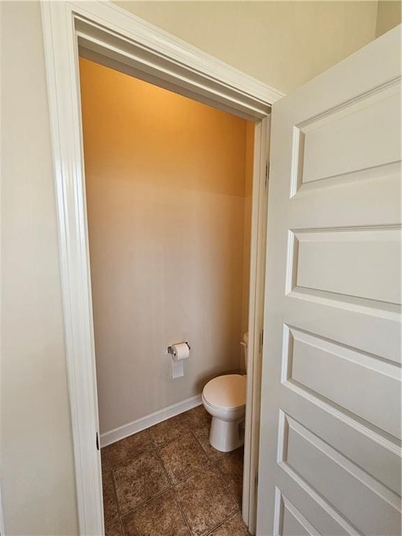 bathroom with toilet, baseboards, and tile patterned floors