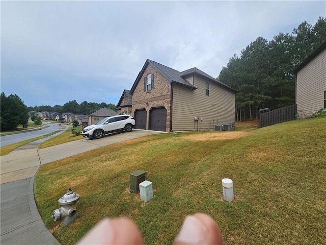 view of side of property with a garage, driveway, a lawn, and brick siding