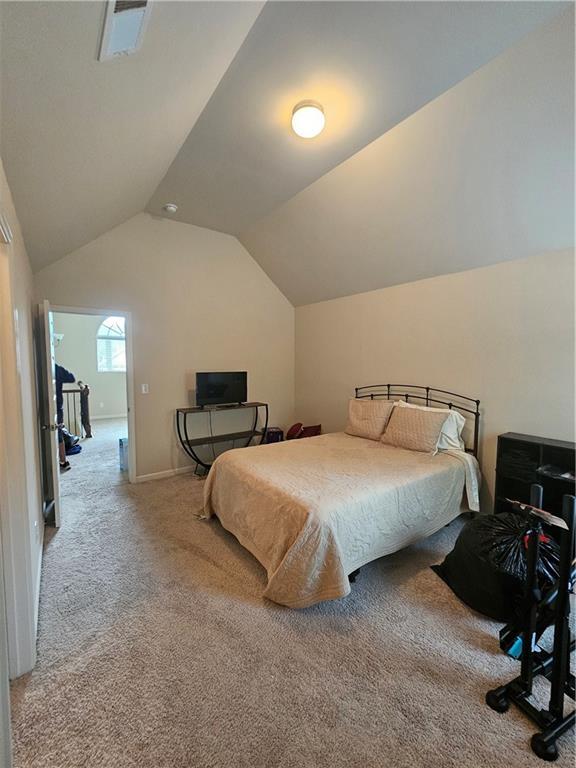 bedroom with carpet floors, lofted ceiling, and baseboards
