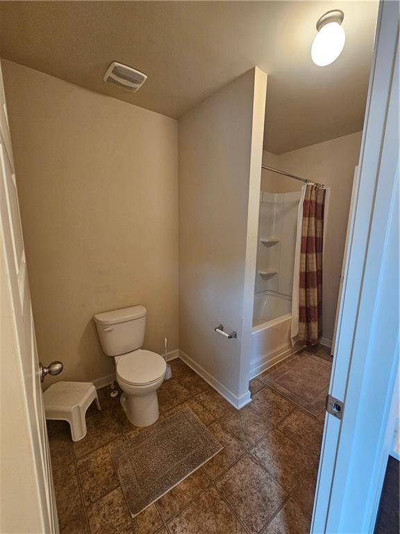 full bath featuring toilet, shower / bath combo with shower curtain, and baseboards