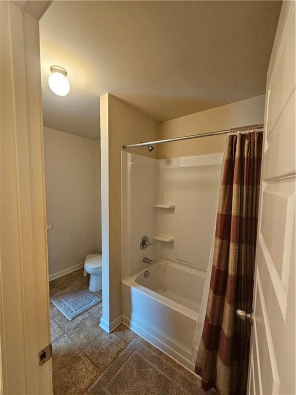 bathroom featuring toilet, shower / tub combo, and baseboards