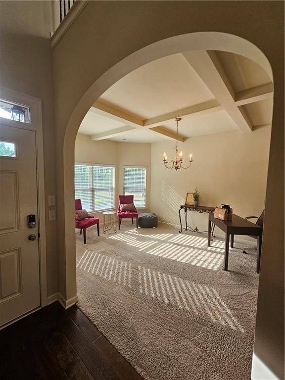 foyer entrance featuring coffered ceiling, arched walkways, dark wood finished floors, beam ceiling, and baseboards
