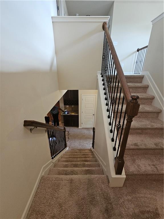 staircase featuring carpet floors and baseboards