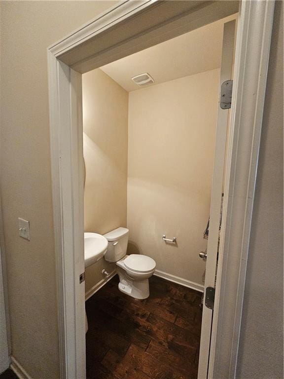 bathroom with wood finished floors, toilet, and baseboards