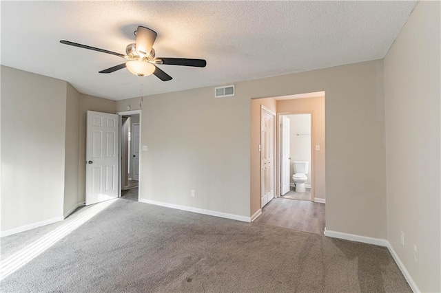 empty room with baseboards, visible vents, a ceiling fan, a textured ceiling, and carpet flooring