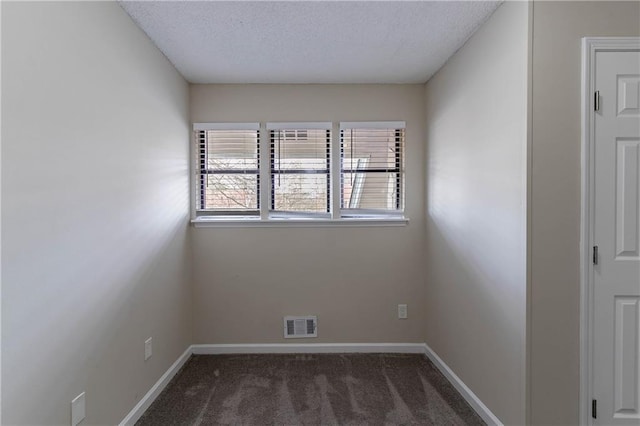 spare room with dark colored carpet, visible vents, a textured ceiling, and baseboards