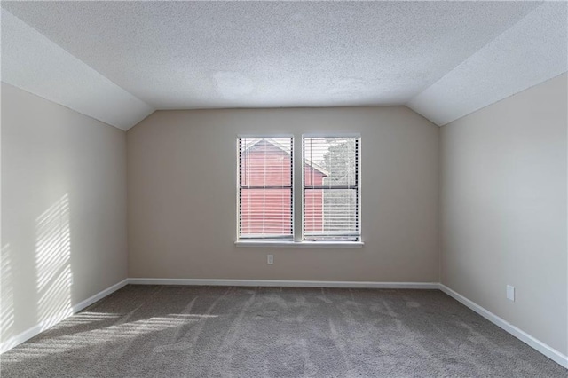 bonus room featuring dark colored carpet, vaulted ceiling, a textured ceiling, and baseboards