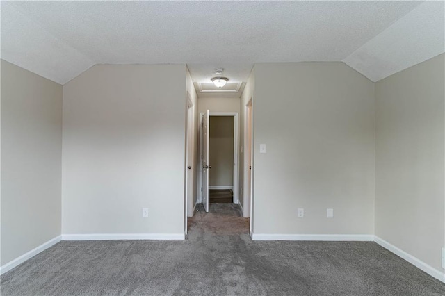 bonus room with lofted ceiling, dark carpet, attic access, a textured ceiling, and baseboards