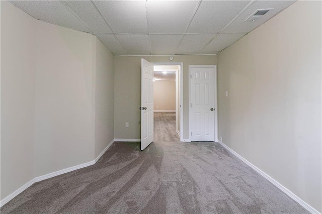 carpeted empty room with a paneled ceiling, visible vents, and baseboards