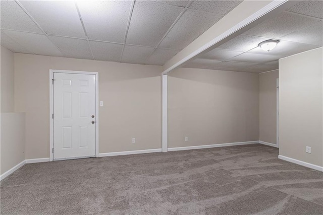 carpeted empty room featuring a paneled ceiling and baseboards