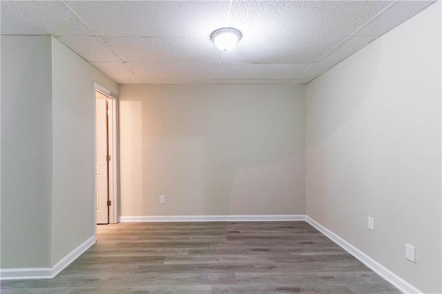 unfurnished room with a paneled ceiling, baseboards, and wood finished floors