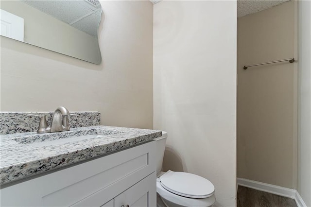 bathroom with toilet, wood finished floors, vanity, and baseboards