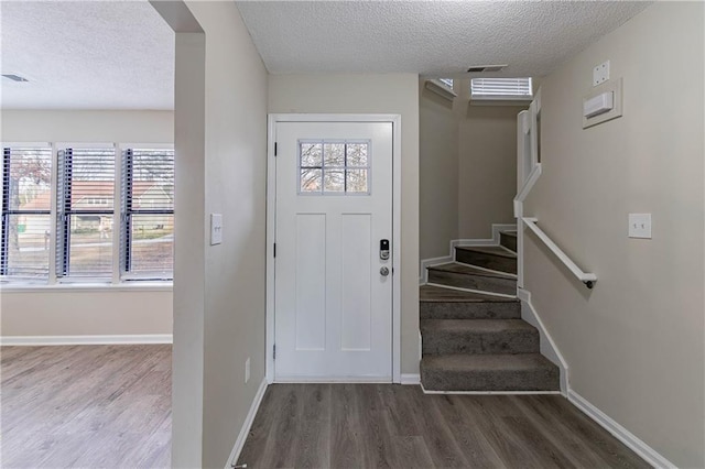 foyer entrance with stairway, dark wood-style flooring, a wealth of natural light, and baseboards