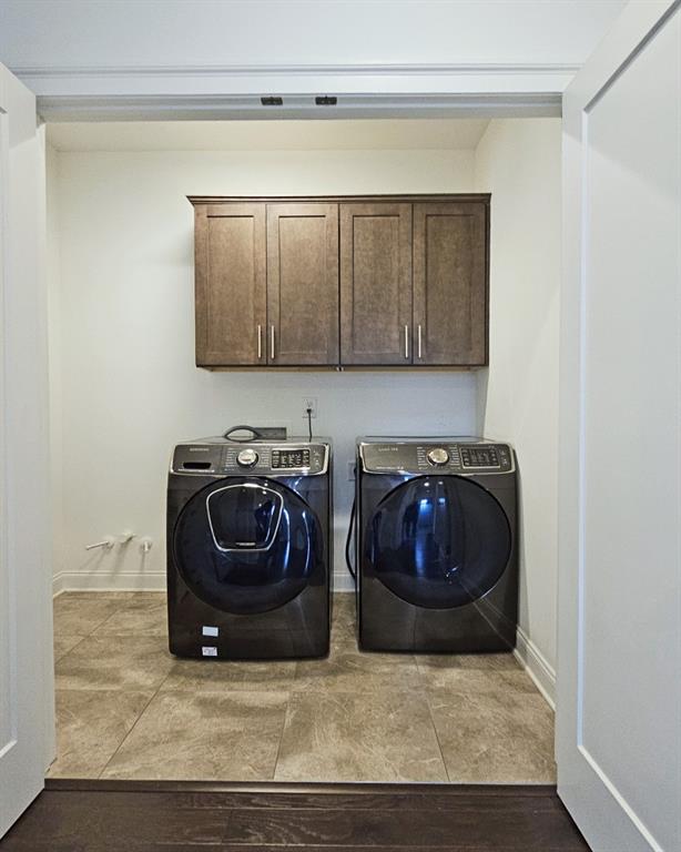 washroom with washer and dryer, light tile patterned flooring, and cabinets