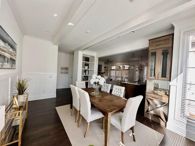 dining area featuring built in features, beamed ceiling, dark hardwood / wood-style floors, and ornamental molding