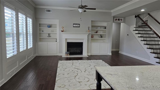 living area featuring ornamental molding, a ceiling fan, dark wood finished floors, stairway, and a fireplace