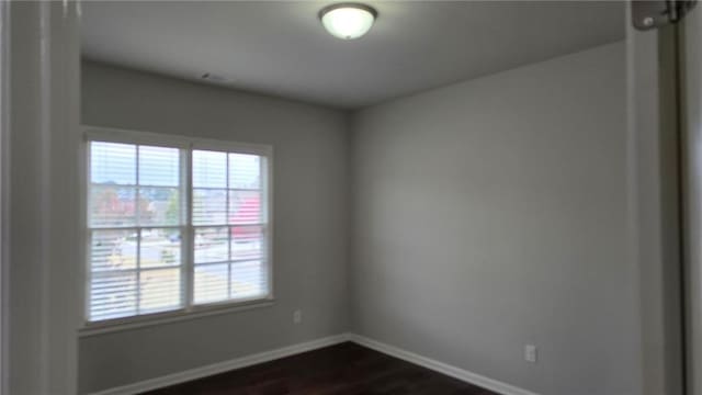 spare room with baseboards and dark wood-style floors
