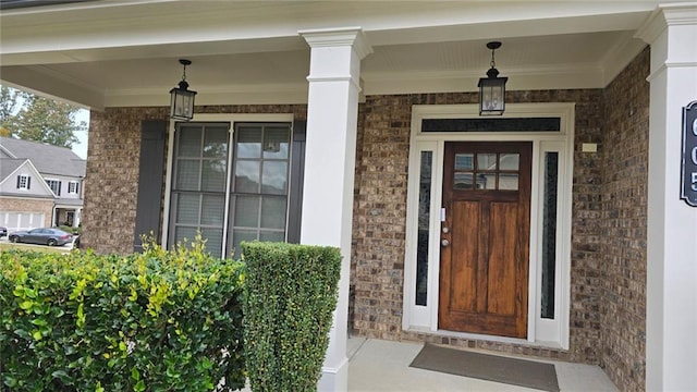 view of exterior entry with brick siding and covered porch