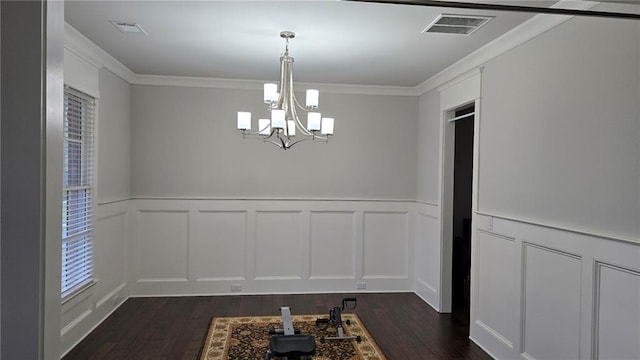 unfurnished dining area with a decorative wall, dark wood-style floors, a chandelier, healthy amount of natural light, and crown molding