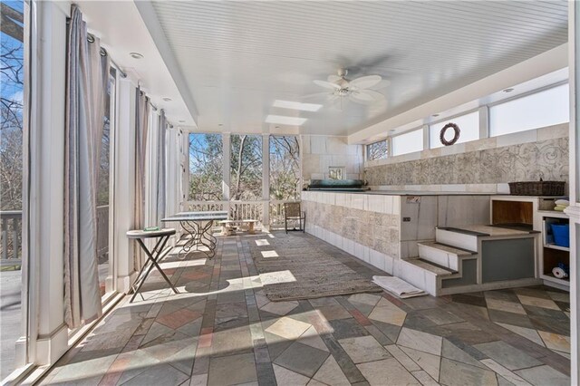 unfurnished sunroom featuring a ceiling fan