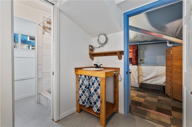 ensuite bathroom with baseboards, connected bathroom, a shower stall, and a sink