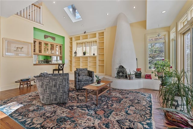 living area featuring built in shelves, a skylight, recessed lighting, wood finished floors, and high vaulted ceiling