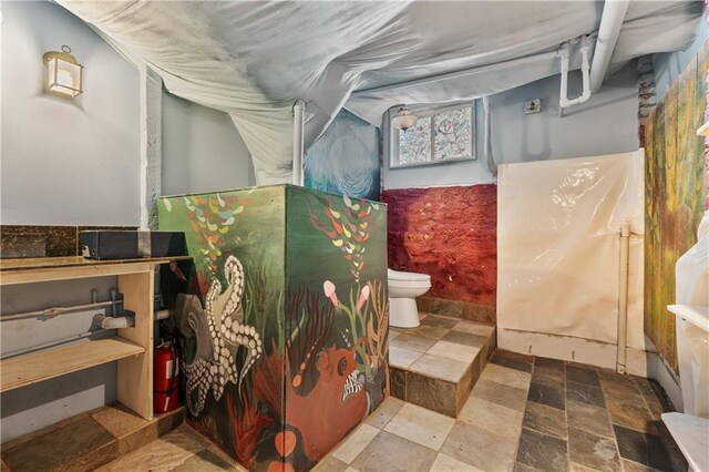 bathroom with toilet and stone finish floor