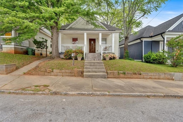 shotgun-style home featuring covered porch and a front yard