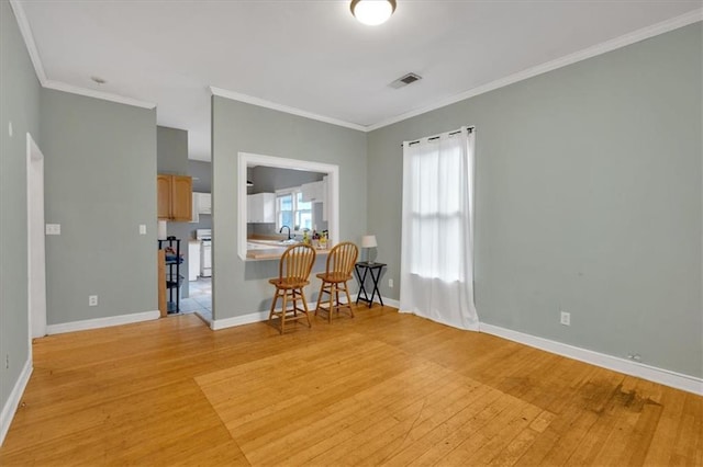 dining space with baseboards, ornamental molding, light wood-type flooring, and visible vents