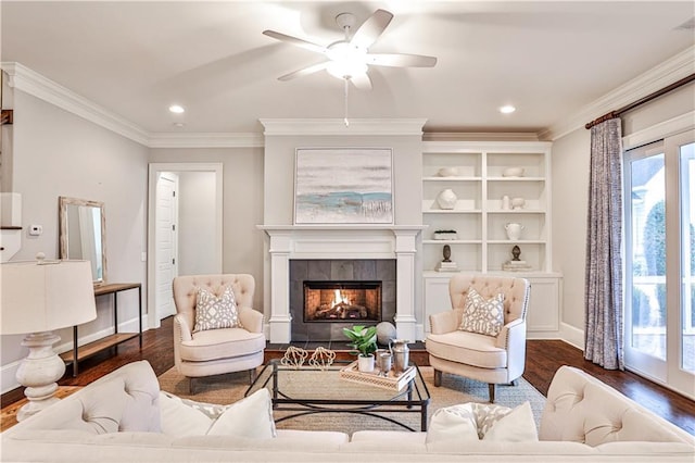living room with ceiling fan, wood finished floors, a tile fireplace, and ornamental molding