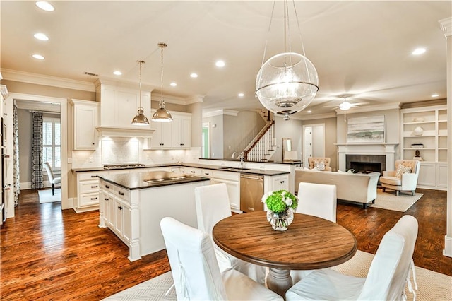 dining space with ceiling fan, dark wood finished floors, ornamental molding, recessed lighting, and a fireplace