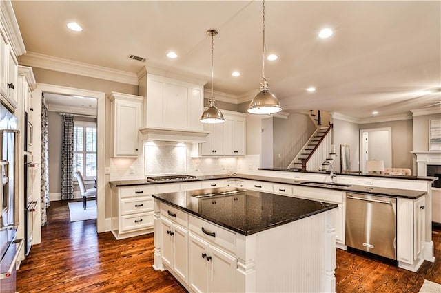 kitchen with visible vents, appliances with stainless steel finishes, a peninsula, and ornamental molding