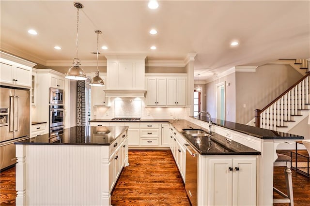 kitchen featuring dark wood-type flooring, a sink, appliances with stainless steel finishes, a breakfast bar area, and a peninsula