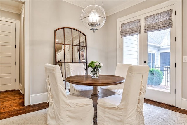 dining room with crown molding, wood finished floors, and baseboards