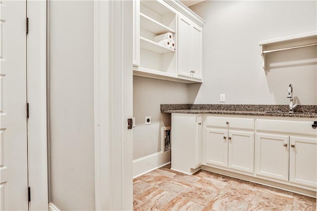 clothes washing area featuring a sink, baseboards, cabinet space, and hookup for an electric dryer