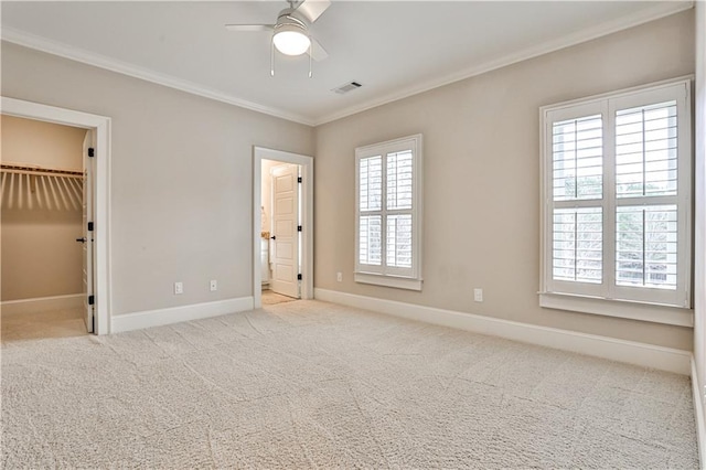 unfurnished bedroom with visible vents, carpet flooring, crown molding, baseboards, and a spacious closet